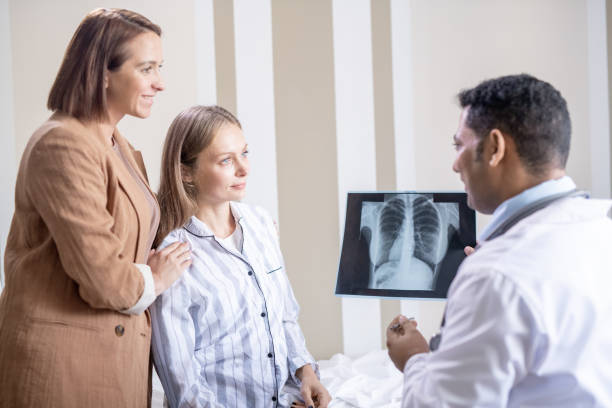 istock Confident radiologist with lung x-ray looking at his patient and her friend 1281932118