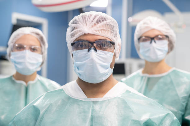istock Young professional male surgeon and his two assistants in protective uniform 1281932152