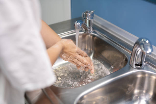 istock Young assistant or surgeon in white uniform washing hands after operation 1281932174
