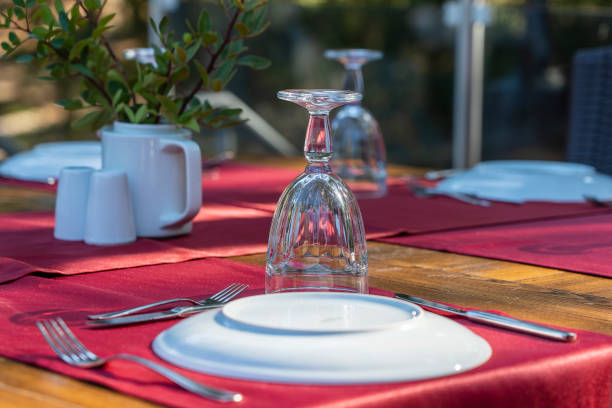 istock Elegant table setting with fork, knife, wine glass, white plate and red napkin in restaurant . Nice dining table set with arranged silverware and napkins for dinner 1281935582