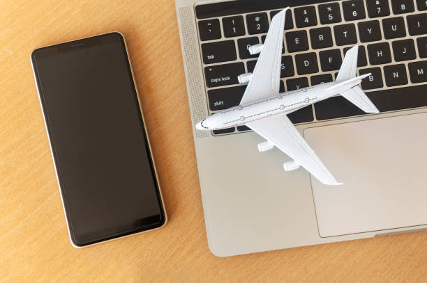 istock Smartphone near laptop computer and airplane on table. Online ticket booking concept 1281936467