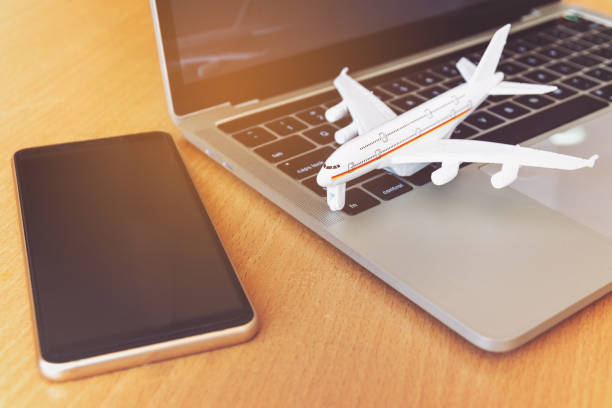 istock Smartphone near laptop computer and airplane on table. Online ticket booking concept 1281936470
