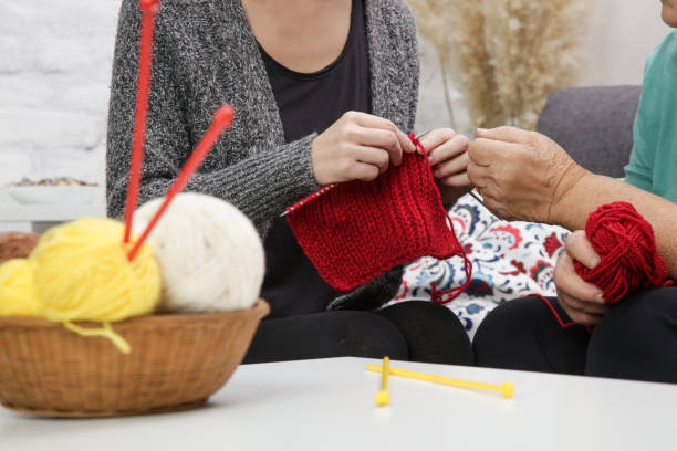 istock Grandomther and granddaughter spending quality time together in creative and fun ways whilst strengthening their family bonds. Senior woman teaching young woman how to knit. Craft and DIY concept. 1281937393