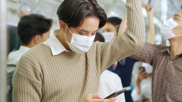 istock Traveler wearing face mask while using mobile phone on public train 1281938833