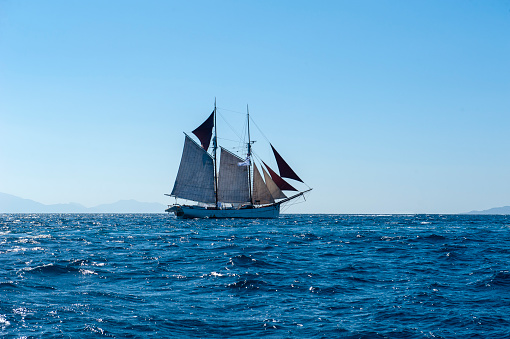 Grand view of an old sailing ship from the times of pirates and the Middle Ages on the high seas with big waves and with a beautiful sky