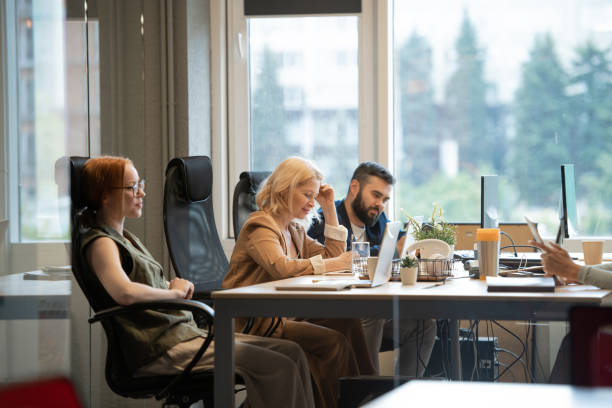 istock Happy mature businesswoman making notes by desk between two young colleagues 1281952019
