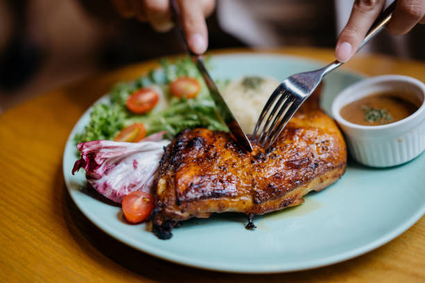 uma mulher asiática desfrutando de uma refeição de frango grelhado em restaurante - comfort foods - fotografias e filmes do acervo