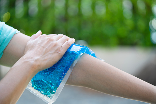 woman putting an ice pack on her arm pain, healthy and medical concept