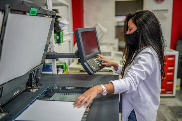 beautiful woman with face mask making copies with copy machine - print shop imagens e fotografias de stock