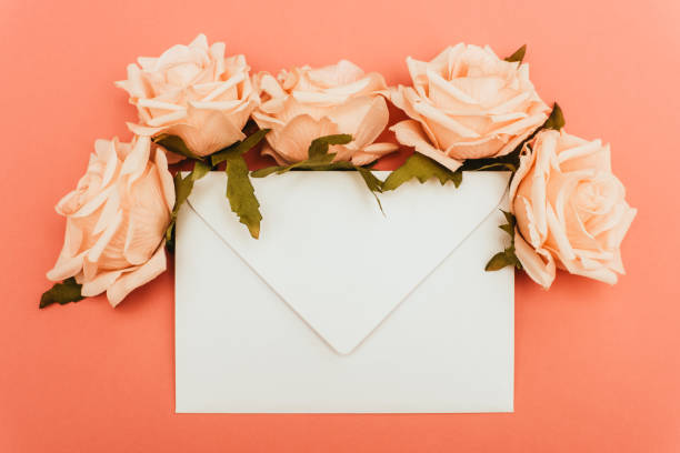 istock top view of white envelope and roses on coral background 1281960479