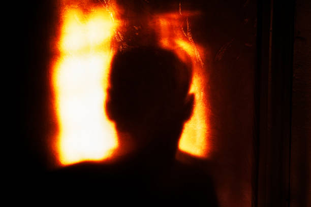 White candle burning with orange flame on black background.