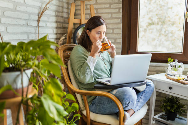 Young Woman drinking her winter tea while working at home stock photo
