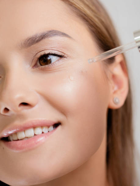 Care for the skin, moisturizing the skin. Young and cute brunette Care for the skin, moisturizing the skin. Young and cute brunette uses oils and facial serum liquid foundation face stock pictures, royalty-free photos & images