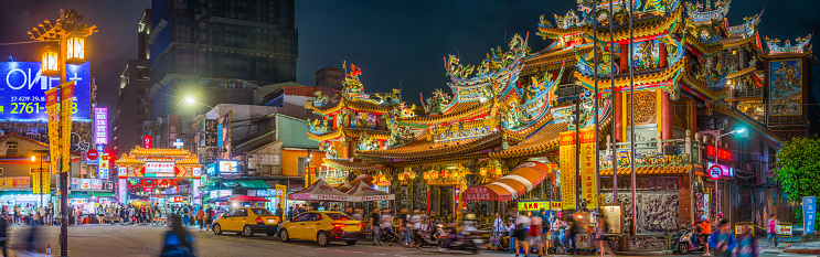 The ornate facade of Songshan Ciyou Temple beside the crowded pavements of Raohe Street Night Market in the heart of Taipei, Taiwan’s vibrant capital city.