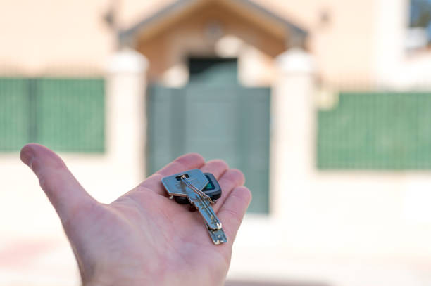 istock Human hand hold a house key on house background 1281963934