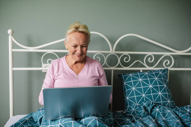istock Senior woman relaxing in bed and using laptop 1281965480