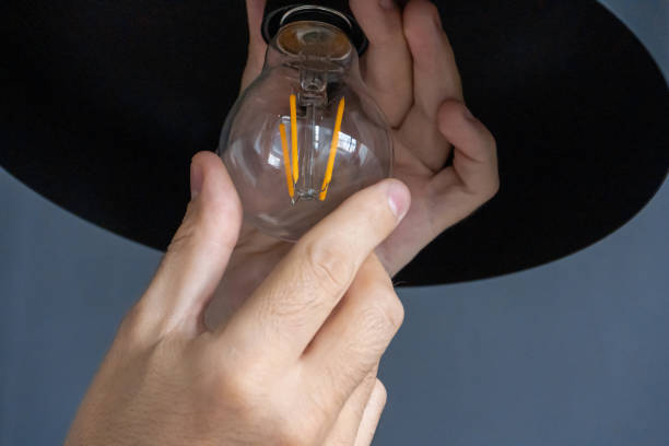 istock Close-up. A hand changes a light bulb in a stylish loft lamp. Spiral filament lamp. Modern interior decor. 1281968099