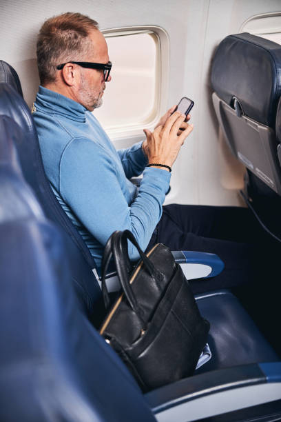 istock Airplane passenger in a jumper texting on the cellphone 1281970214