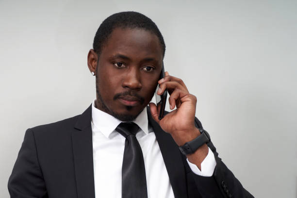 istock Closeup of angry young african man screaming while talking on smartphone over grey background 1281973345