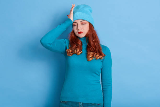 istock Tired sick lady with red curlers posing with closed eyes, suffering from terrible headache, wearing casual clothing, keeping hand on head, being ill, has high fever. 1281973875