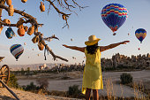 Beautiful woman watching colorful hot air balloons flying over the valley at Cappadocia, Turkey.