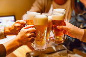 居酒屋で乾杯する多くの人々の手とマグビール