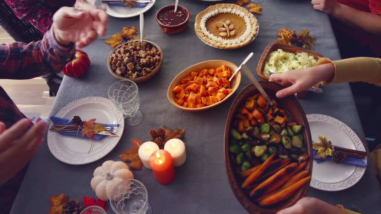 Family Having Traditional Holiday Dinner with Stuffed Turkey, Roasted Potatoes, Cranberry Sauce, Vegetables and Pumpkin Pie