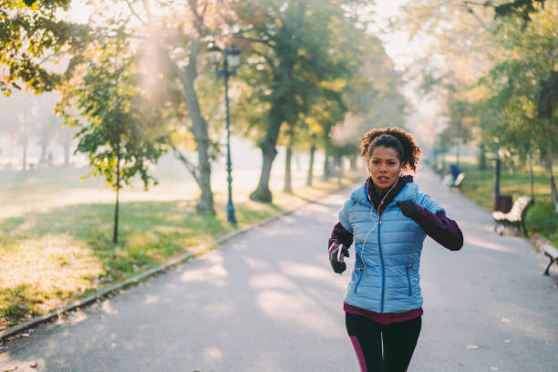Jogging in autumn park Woman sports training among nature cardiovascular exercise stock pictures, royalty-free photos & images