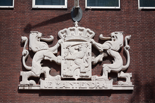 Insignia of Netherlands with three lions at facade in Venlo. Text is Je Maintiendrai - I will withstand, official motto of Holland. Building is postal office Postkantoors from 1938 made by architect Hoekstra
