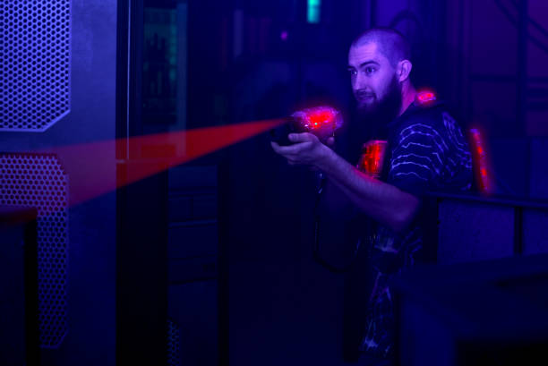 istock laser tag player holding gun shooting light in black light labyrinth 1281987711