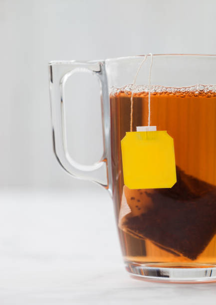 istock Yellow label tag black tea teabag in clear glass cup on white 1281987911