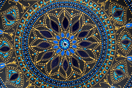 Decorative ceramic plate with black, blue and golden colors, painted plate on background, closeup, top view. Detail porcelain plate painted with acrylic paints, handwork, dot painting