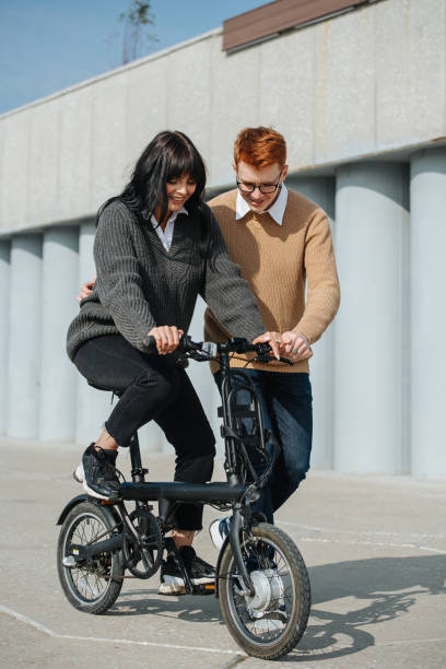 istock Happy moments. Young man helping girlfriend ride ebike, supporting her. 1281988437