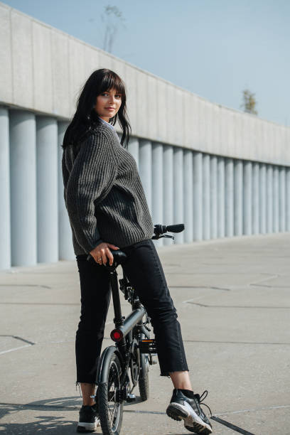 istock Beautiful black-haired woman sitting on ebike, looking over shoulder at camera 1281988445