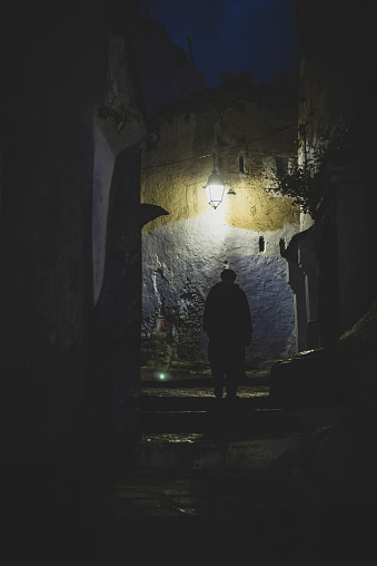 A Moroccan man walks in an alley at night in the famously blue city of Chefchaouen, Morocco.