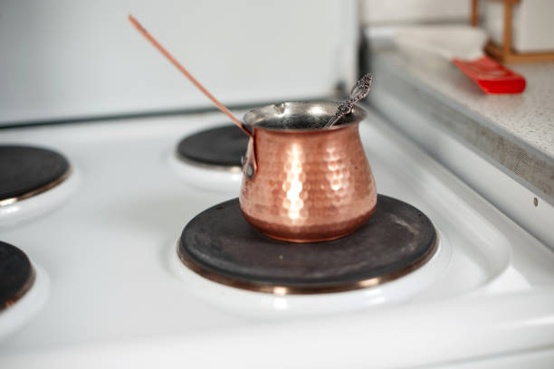 coffee is prepared in a coffee pot (cezve) on a white stove. small focus area, selective focus.