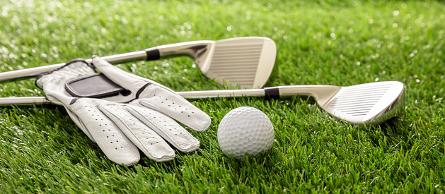 Golf equipment, sticks, glove and golfballs on green course lawn, close up view, banner. Golfing sport and club concept