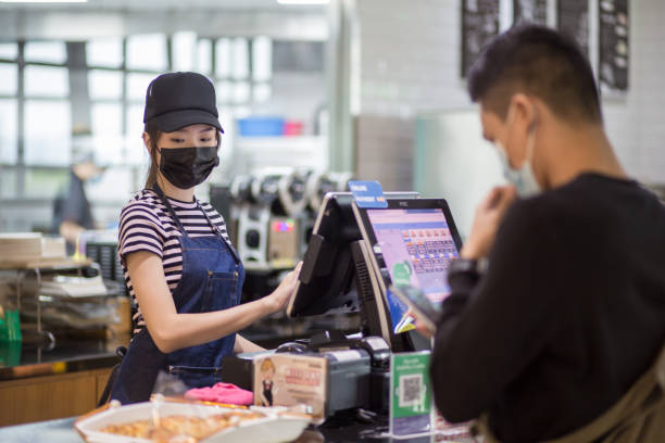 istock Asian Chinese cafe cashier with mask helping customer packing and checkout. Customer using mobile wallet for the payment. 1281995796