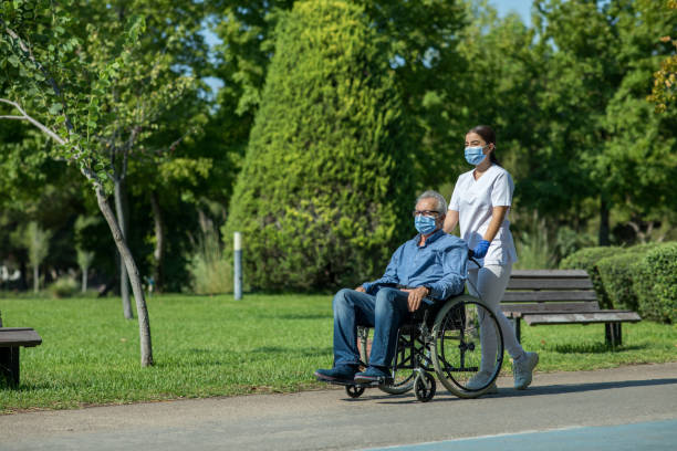 nurse taking patient for a stroll in garden - wheelchair disabled senior adult female nurse imagens e fotografias de stock
