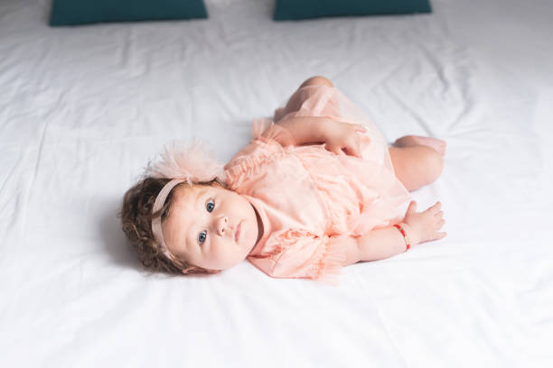 Portrait of adorable baby girl lying on bed at home
