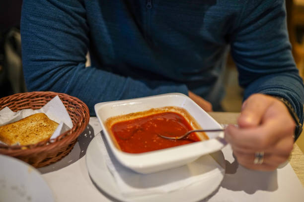 istock Young man sitting in restaurant and eating tomato soup 1282008441