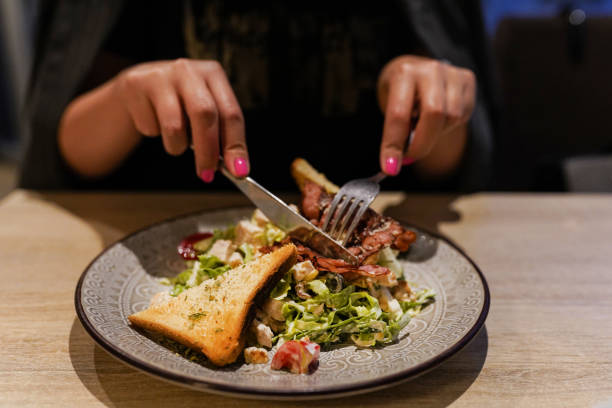 Young woman sitting in restaurant and eating caesar salad