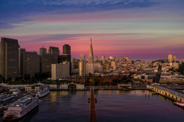 Aerial View of San Francisco Skyline An aerial view of the San Francisco Skyline with a dramatic sunset  sky. City lights twinkle in the skyscrapers and the pier is illuminated against the bay. transamerica pyramid san francisco stock pictures, royalty-free photos & images