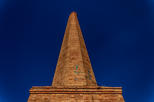 Large chimney of old abandoned factory in Alcoi, Alicante, Spain.