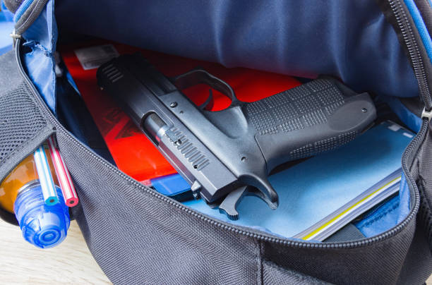 Loaded 9mm pistol in the school backpack. School shootings, gun control concept image. Loaded 9mm pistol in the school backpack. School shootings, gun control concept image. gun control photos stock pictures, royalty-free photos & images