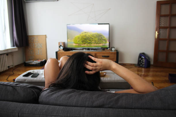istock Woman relaxing on sofa and watching tv 1282017394