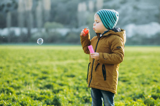 istock Child plays with soap bubbles on the green grass. 1282020905