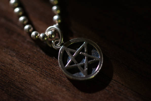 istock Silver Pentagram charm old necklace on a dark brown wooden surface, moody background 1282021949