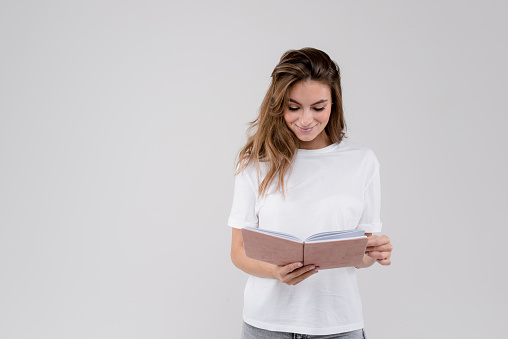 Beautiful lady holding diary and making day plan on white background with copy space for text