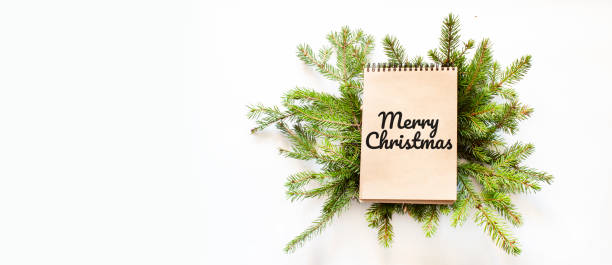 istock Brown notepad lying on branches of a christmas tree with text Merry Christmas 1282038158